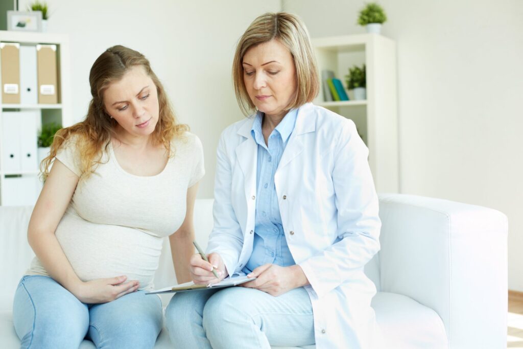pregnant woman talking her doctor room min