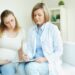 pregnant woman talking her doctor room min