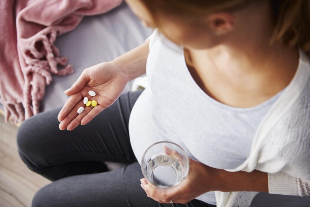 young pregnant woman taking medicine min