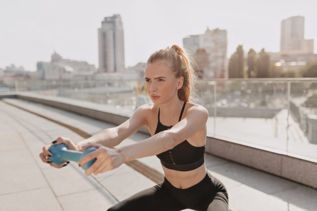 young woman practice stretching outdoor with hand dumbbells sunlight high quality photo min