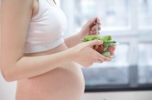 Mujer embarazada comiendo alimentos que son buenos para tener ácido fólico en el embarazo