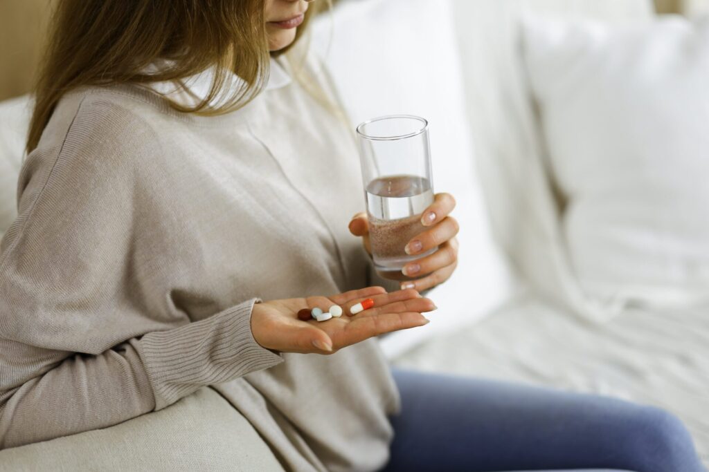 close up woman holding pills time take medications cure headache high blood pressure pain killer drugs home stay home concept coronavirus pandemic min