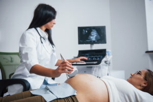 Doctora realizando una ecografía previa a embarazada para hacer la prueba amniocentesis