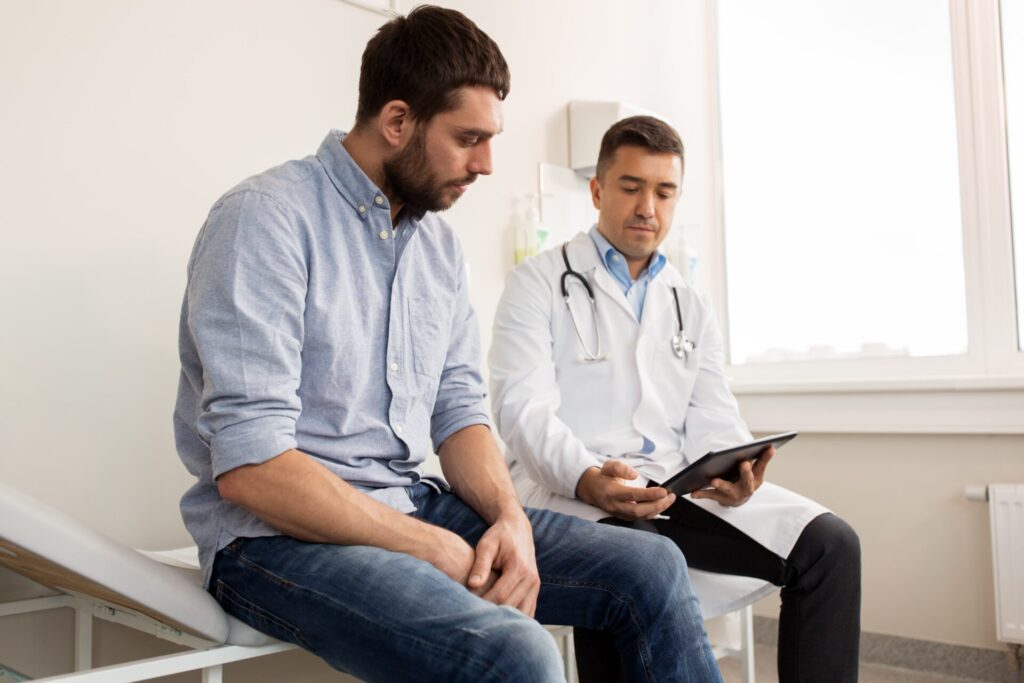 medicine healthcare people concept doctor with clipboard young male patient having health problem meeting hospital min