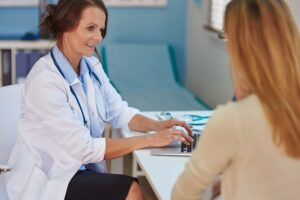 Mujer en consulta médica preguntado por la consecuencias de quitar el útero por miomas