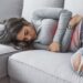 mujer joven con dolor de estomago acostado en la cama min