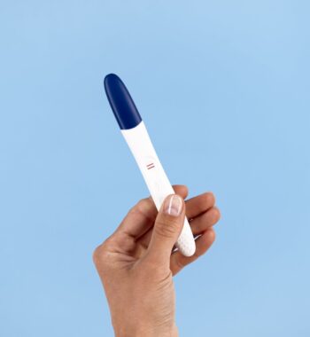 hand holding positive pregnancy test min hand holding positive pregnancy test min